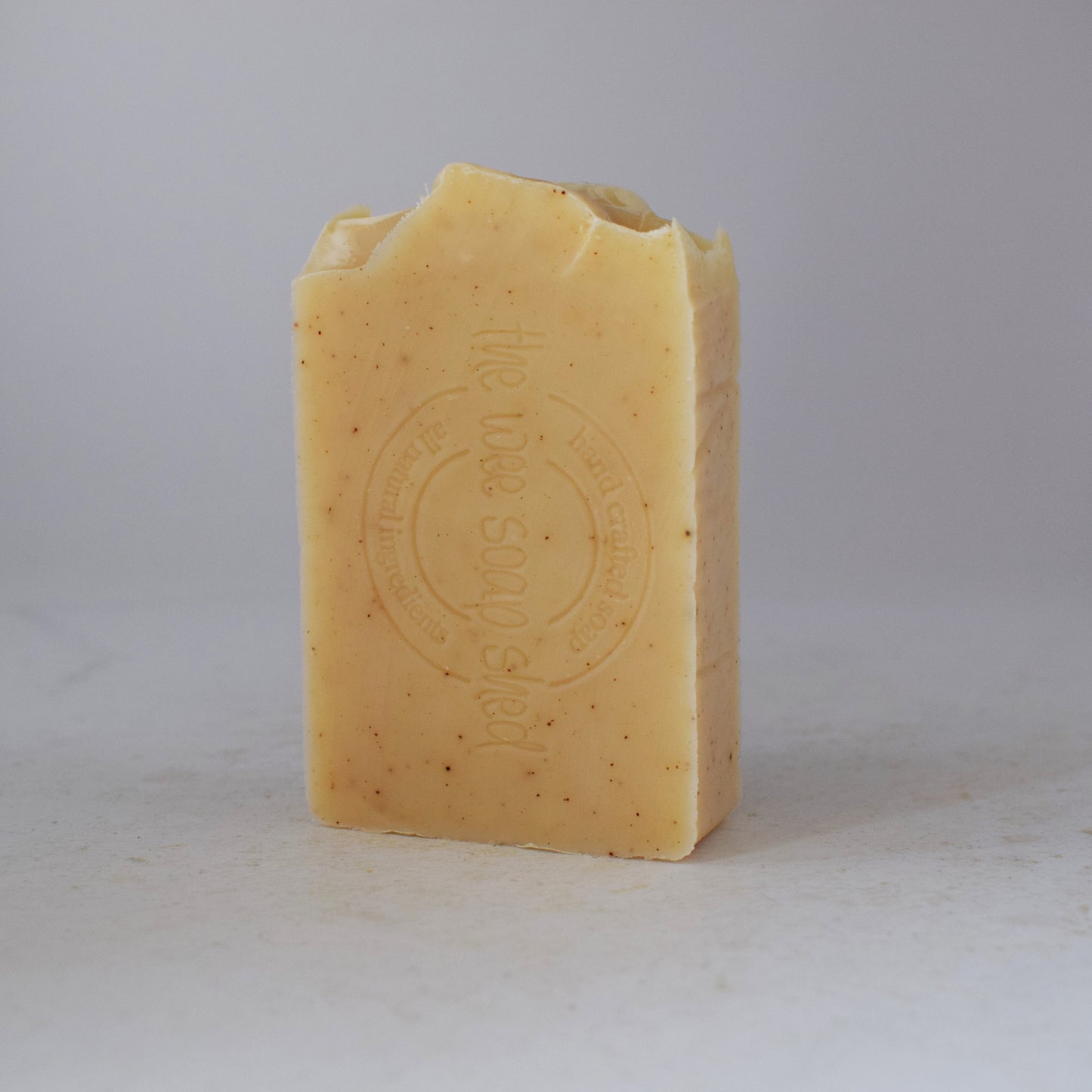Pale yellow soap bar stamped with logo on a white bacground