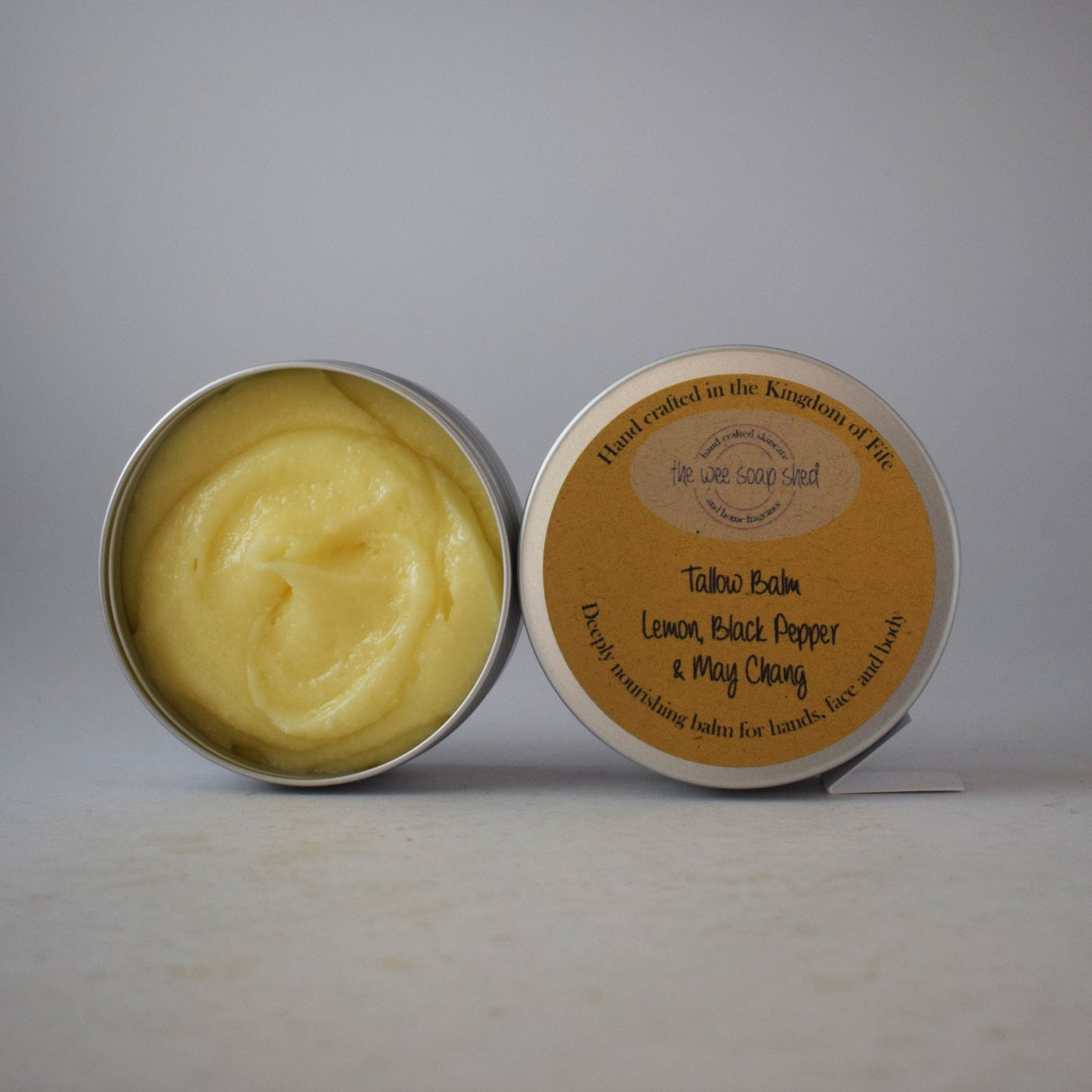 Tin of yellow balm with a label on a gray background
