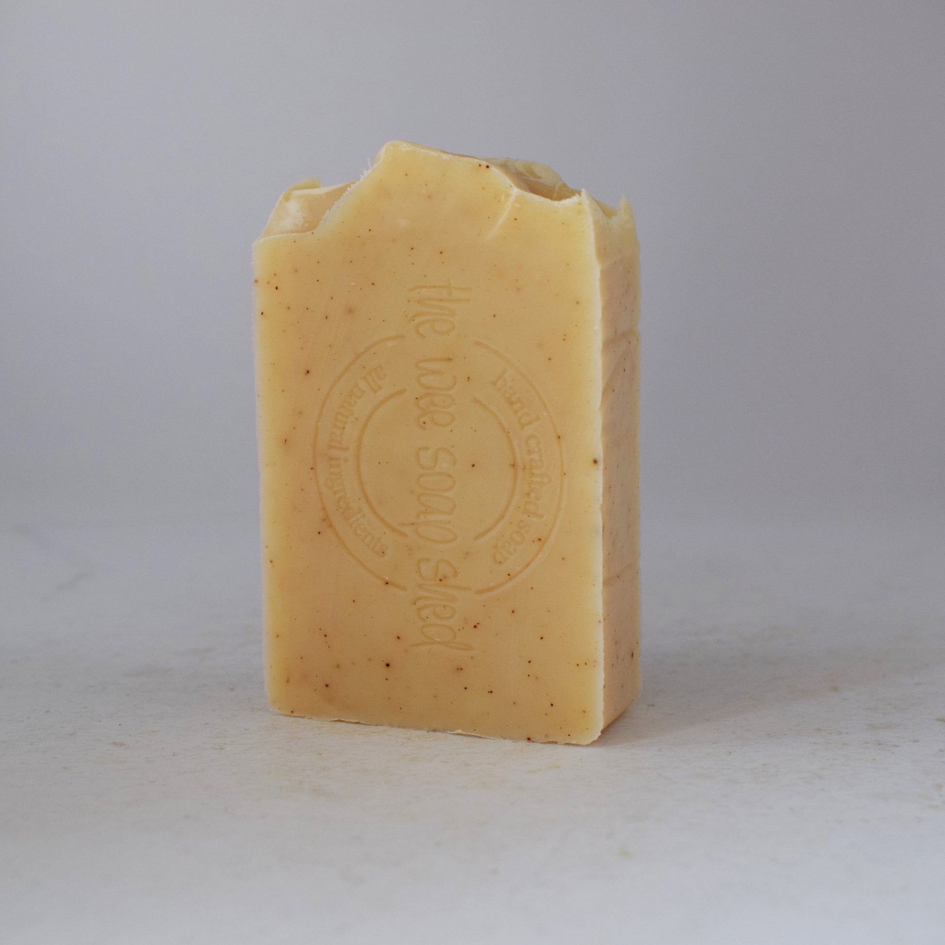 Pale yellow soap bar stamped with logo on a white bacground