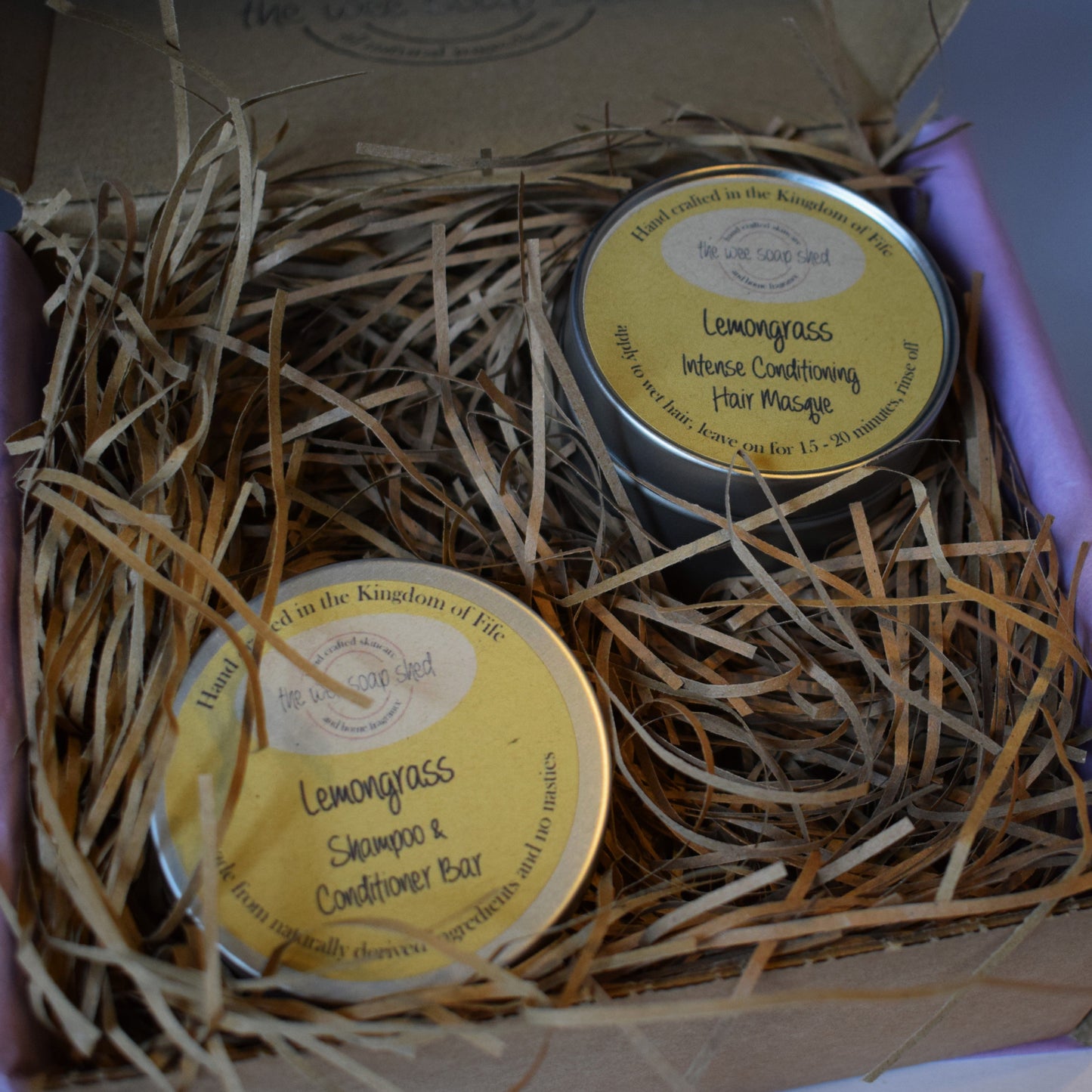 Two tins of Lemongrass shampoo and conditioner bars in a box with straw bedding.