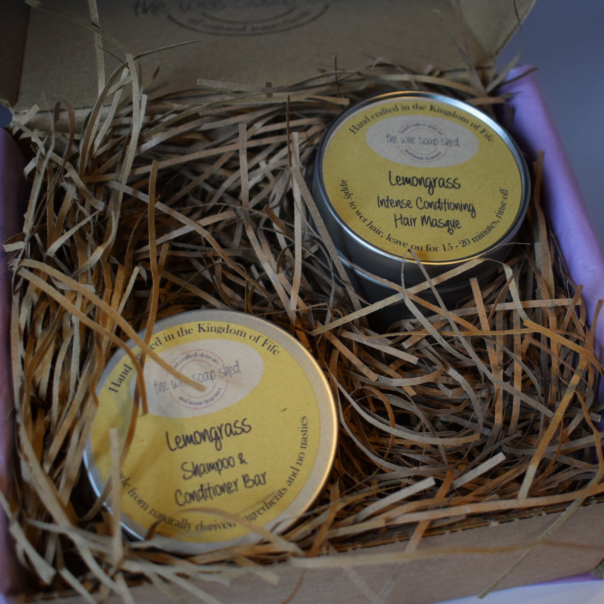 Two tins of Lemongrass shampoo and conditioner bars in a box with straw bedding.