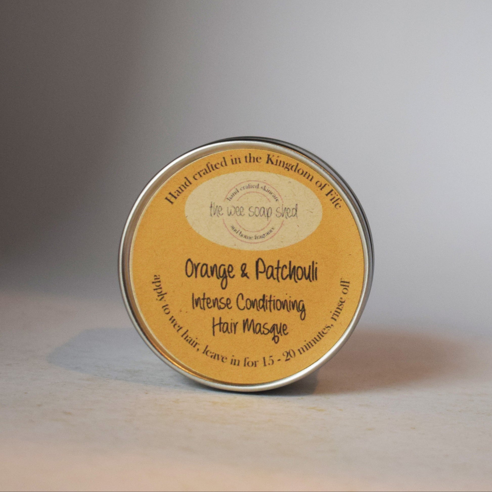 Tin of hair product with a yellow label on a gray background